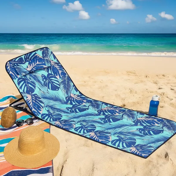 Saltea impermeabila pliabila ABYZ albastra cu model tropical, accesorizata cu palarie de paie si ochelari de soare pe o plaja insorita.