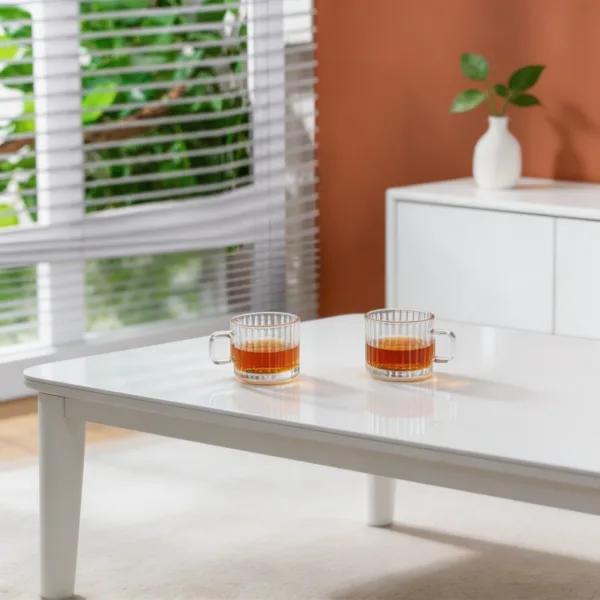 Două cești din sticlă transparentă cu ceai cald așezate pe o masă albă de cafea.