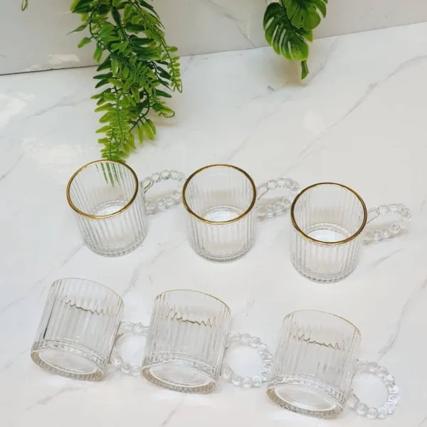 Set cesti cafea ABYZ din sticla transparenta asezate in linie langa frunze decorative